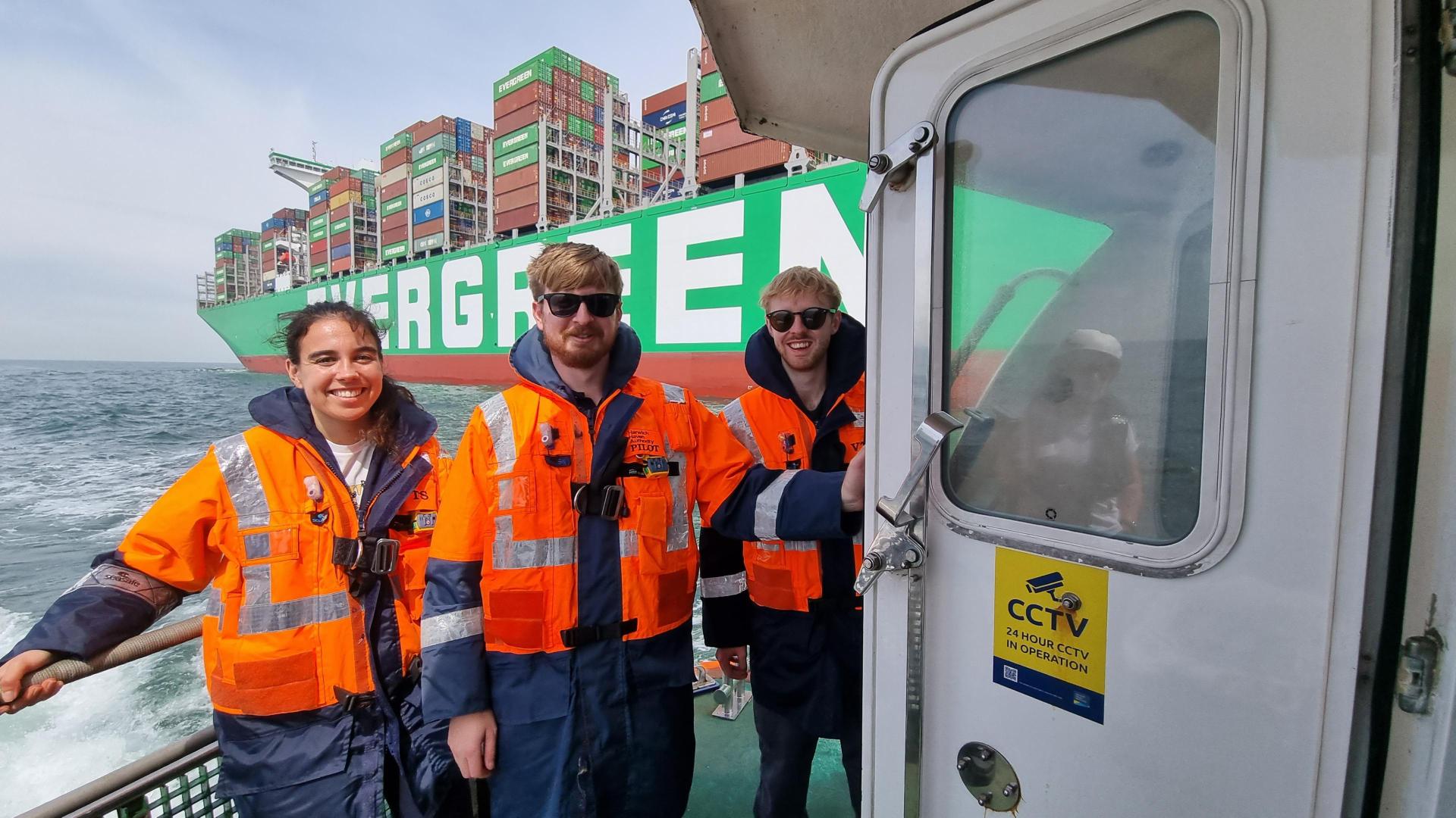 Three graduates with life safety jackets on boats on Port of Felixstowe. 