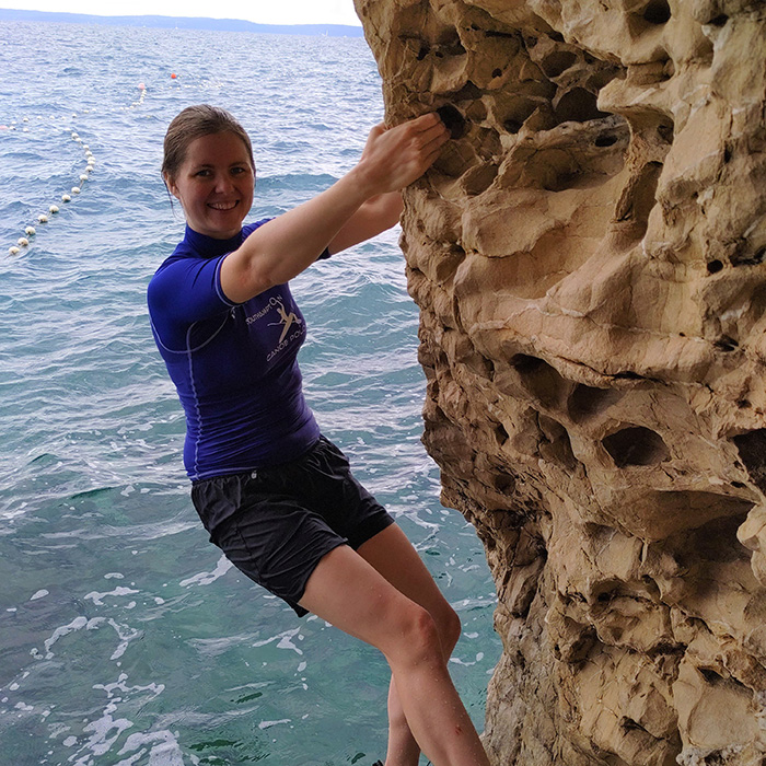 Amelia Couldrey climbing a cliff by the sea in Croatia