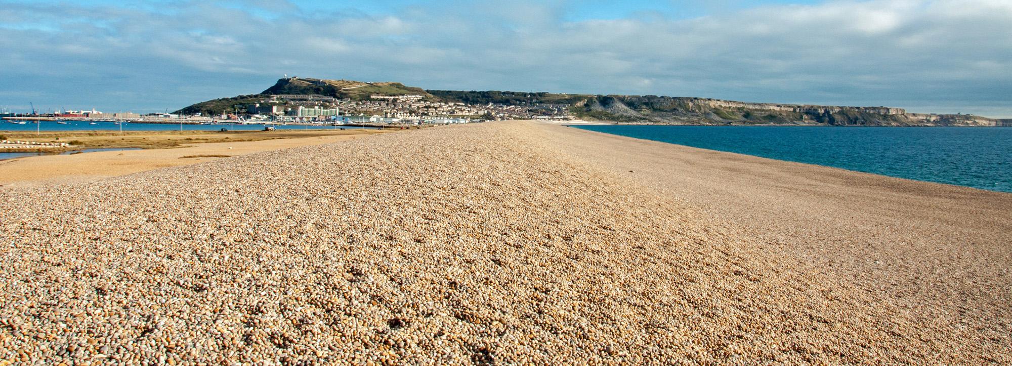 View of Chesil sand beach, UK with houses