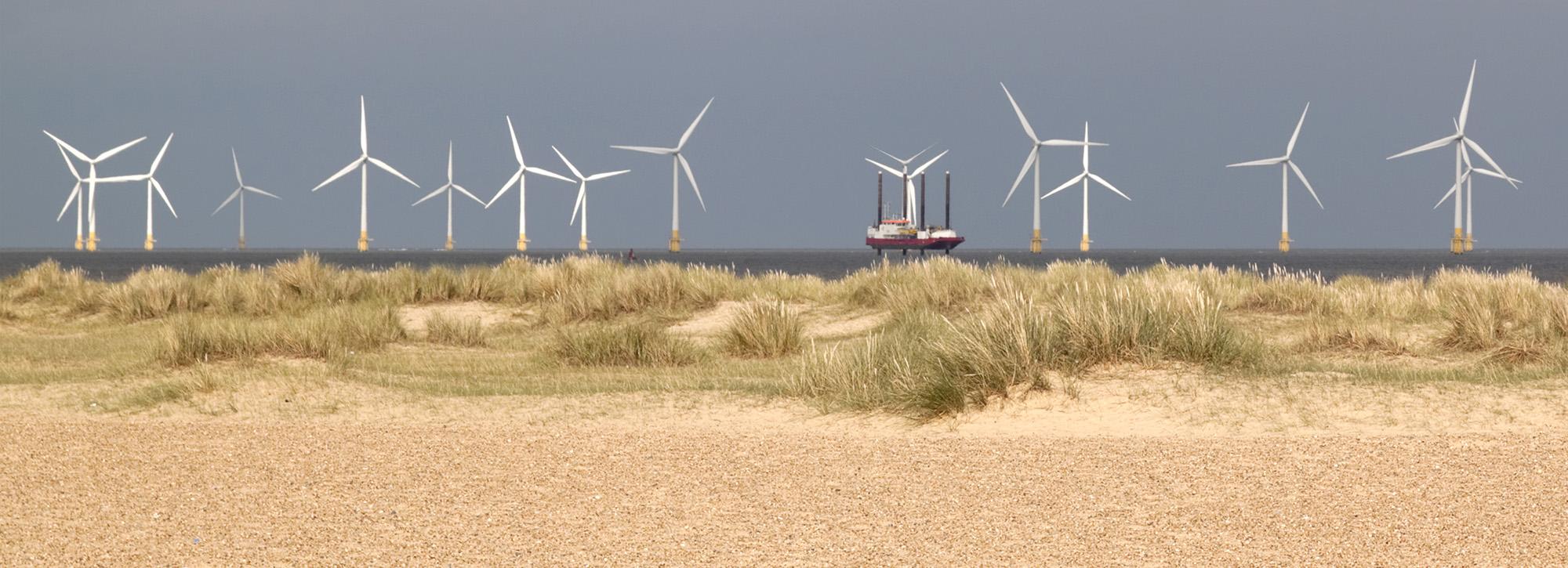 Panoramic view of a wind farm behind sand dunes