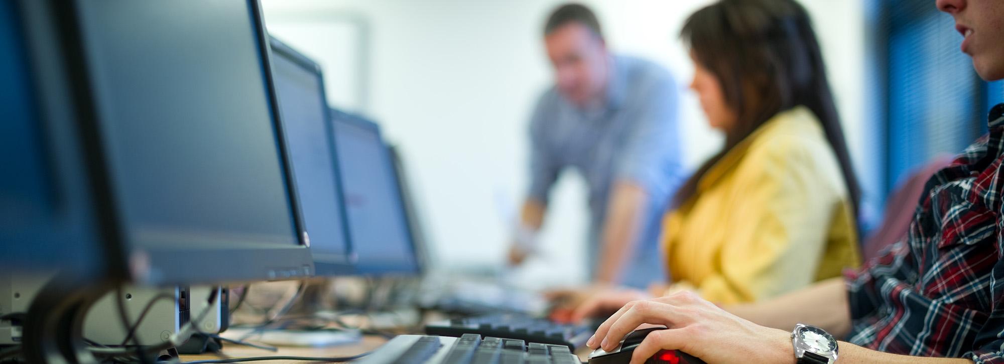 People sitting at desk receiving training on computer