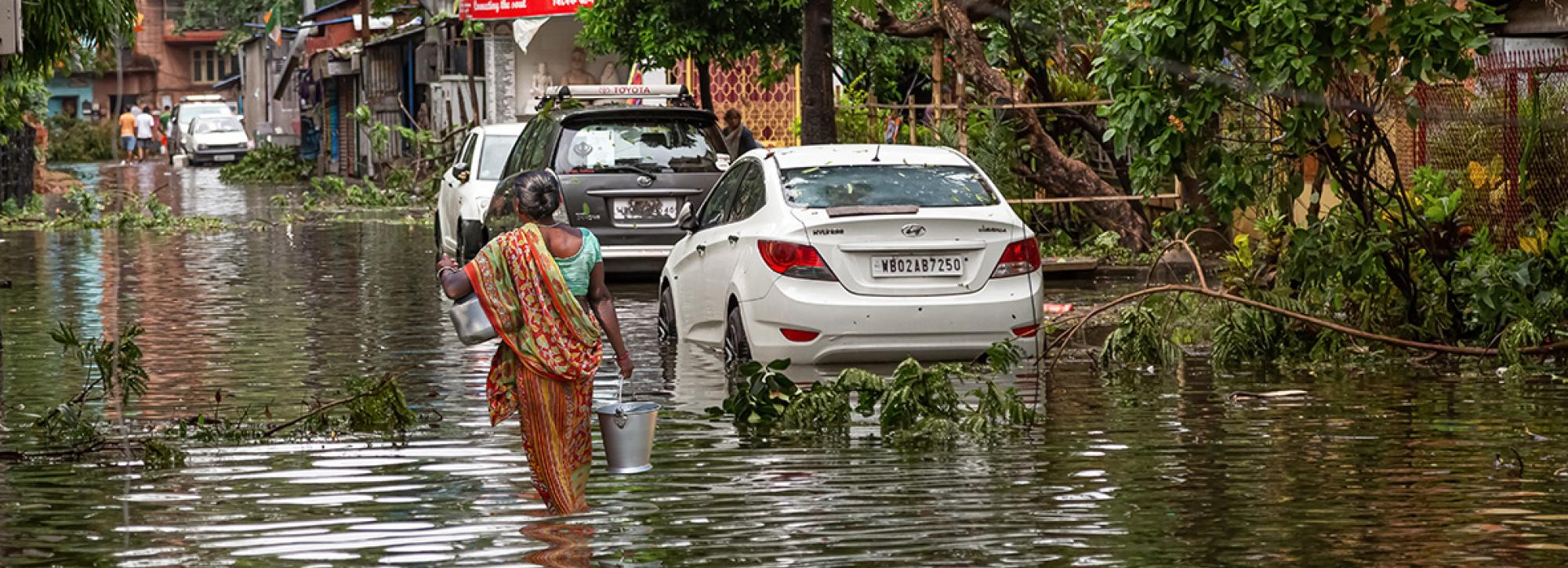 Woman walking through flood water on a street in Kolkata India in the aftermath of Cyclone Amphan