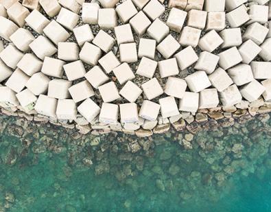 Aerial view of armoured breakwater in green sea waves