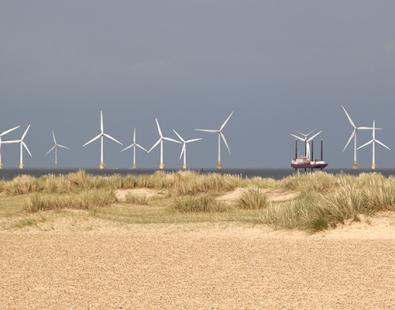 Panoramic view of a wind farm behind natural sand dunes