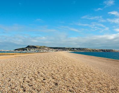 View of a shingle beach under blue sky