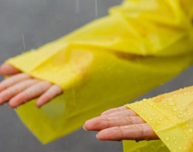 Close up of someone's hands under rain in yellow raincoat