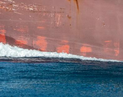 dolphin swimming next to big ship 
