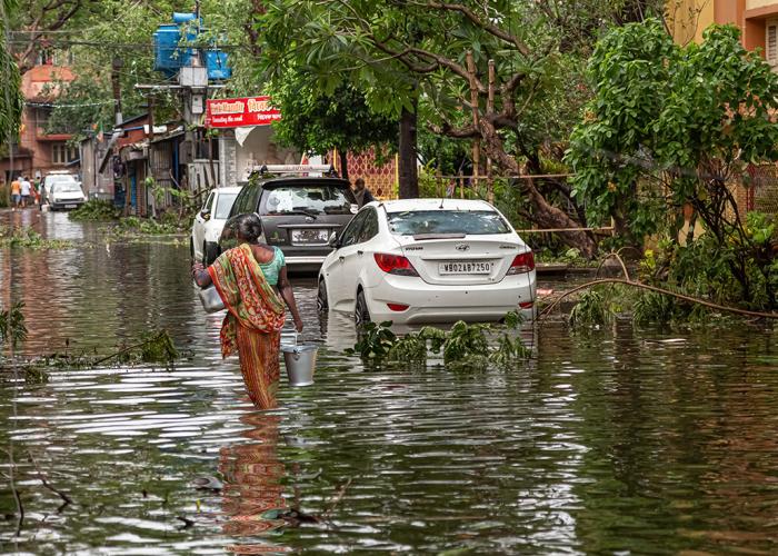 Woman walking through flood water on a street in Kolkata India in the aftermath of Cyclone Amphan