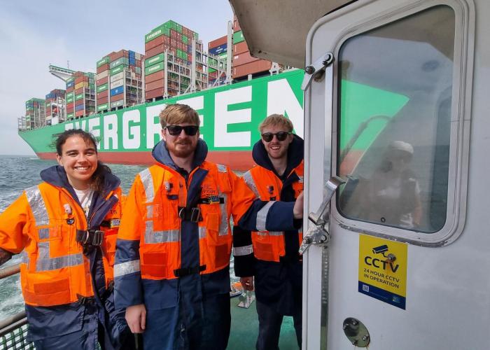 Three graduates with life safety jackets on boats on Port of Felixstowe. 