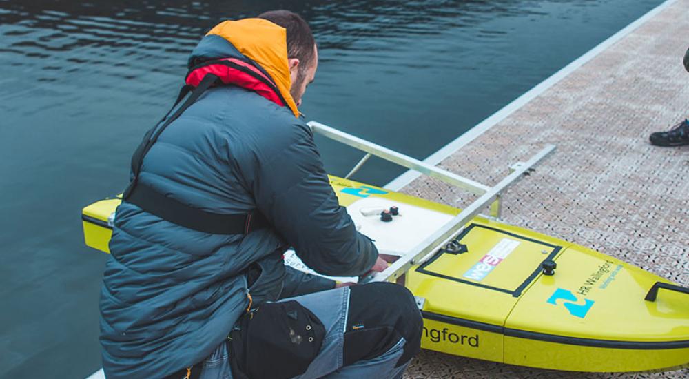 Zac Nash learning over the yellow, surfboard-shaped ARCboat. 