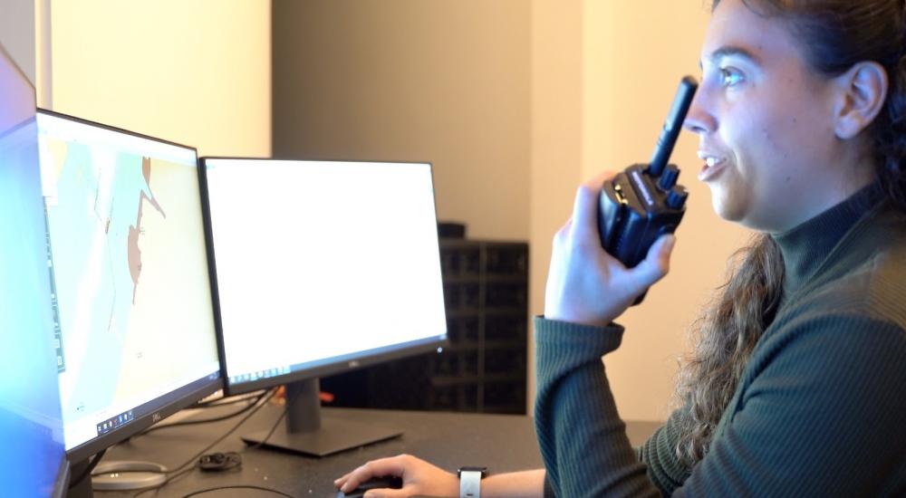 Female ship engineer sitting in front of computer screens with walkie talkie in her hand