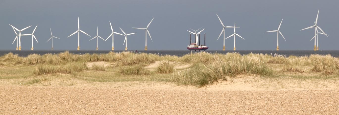 Panoramic view of a wind farm behind sand dunes