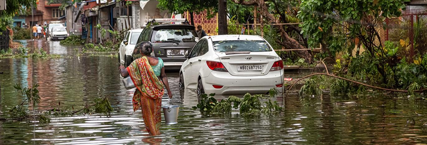 Woman walking through flood water on a street in Kolkata India in the aftermath of Cyclone Amphan