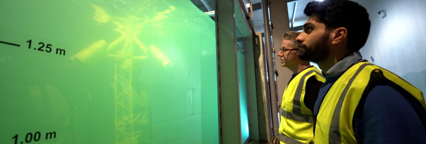 Two HR Wallingford staff looking at the Fast Flow Facility with Stinger Keel model