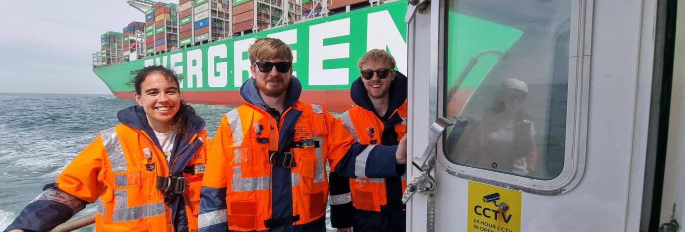 Three graduates with life safety jackets on boats on Port of Felixstowe. 